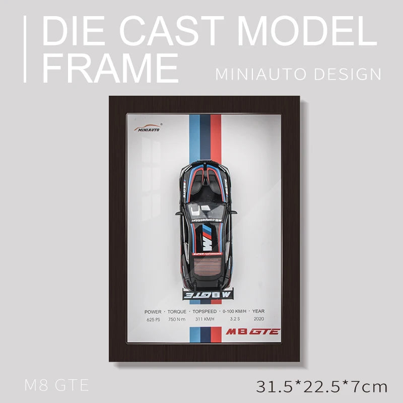Framed diecast model of a black BMW M8 GTE race car with blue, red, and light blue stripes. The frame's dimensions are 31.5 x 22.5 x 7cm.