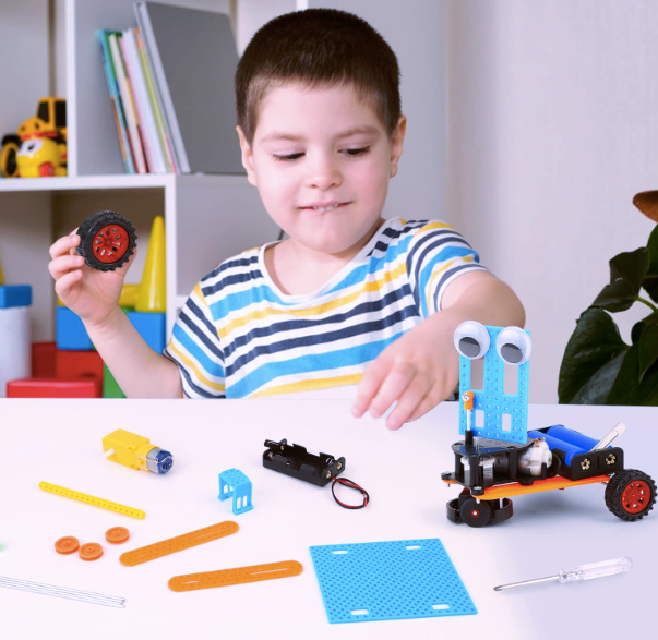 Child building a robot car from a DIY STEM kit with various components on a white table.